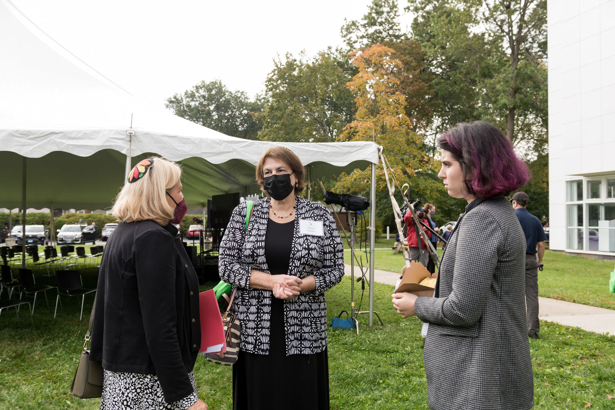 Three women speaking, one wears a kippah