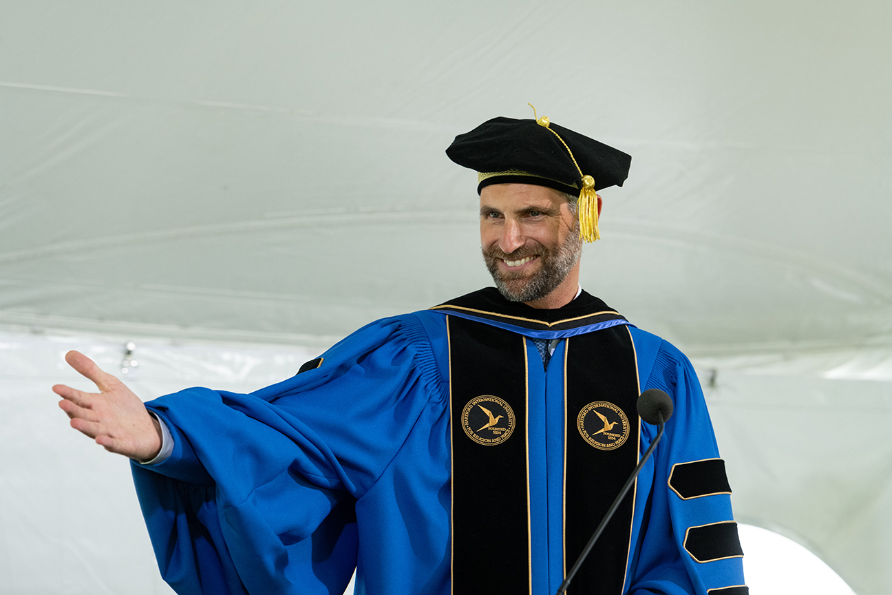 President Lohr smiling and gesturing toward graduates