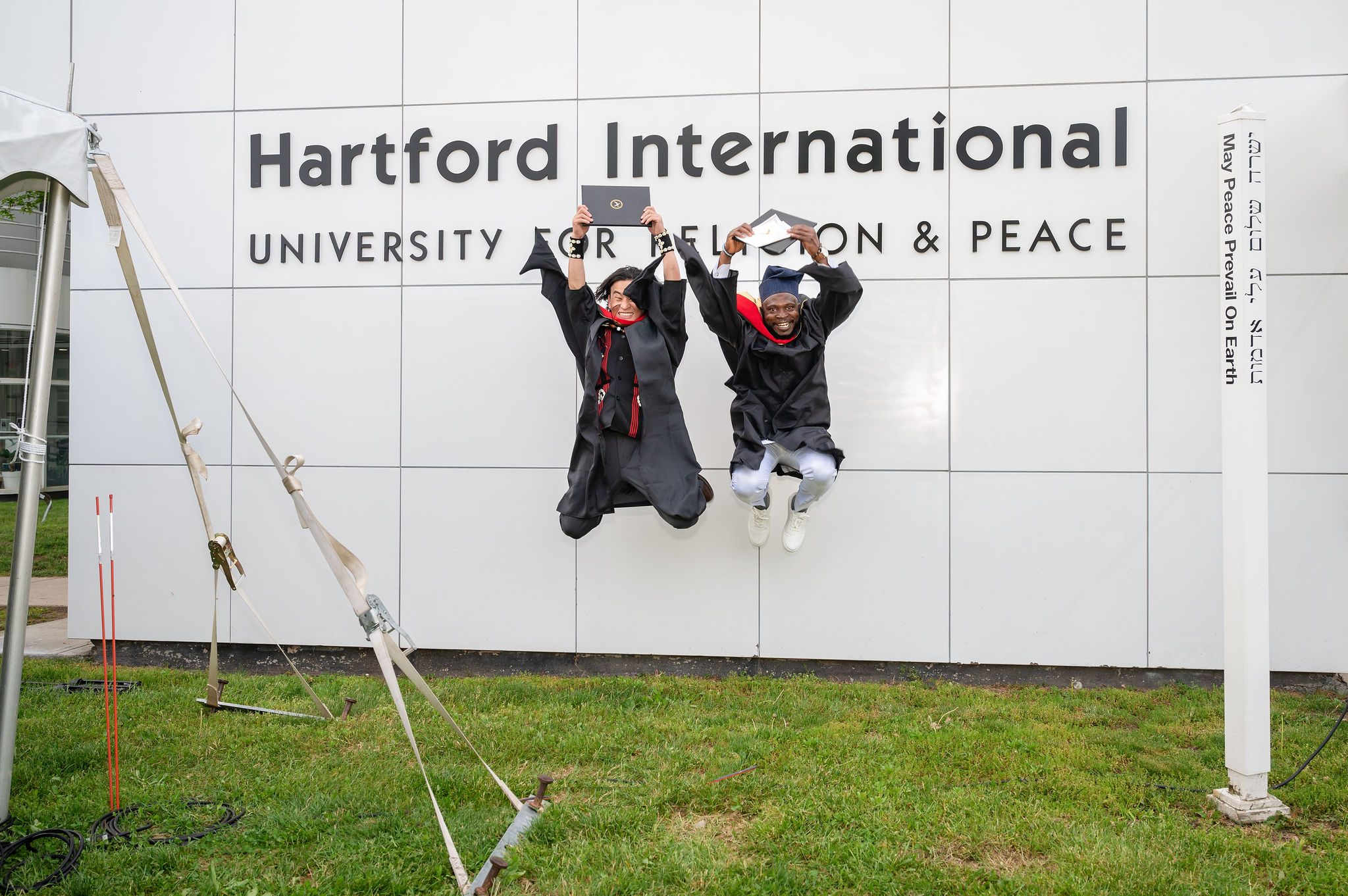 Two people in graduation robes jumping