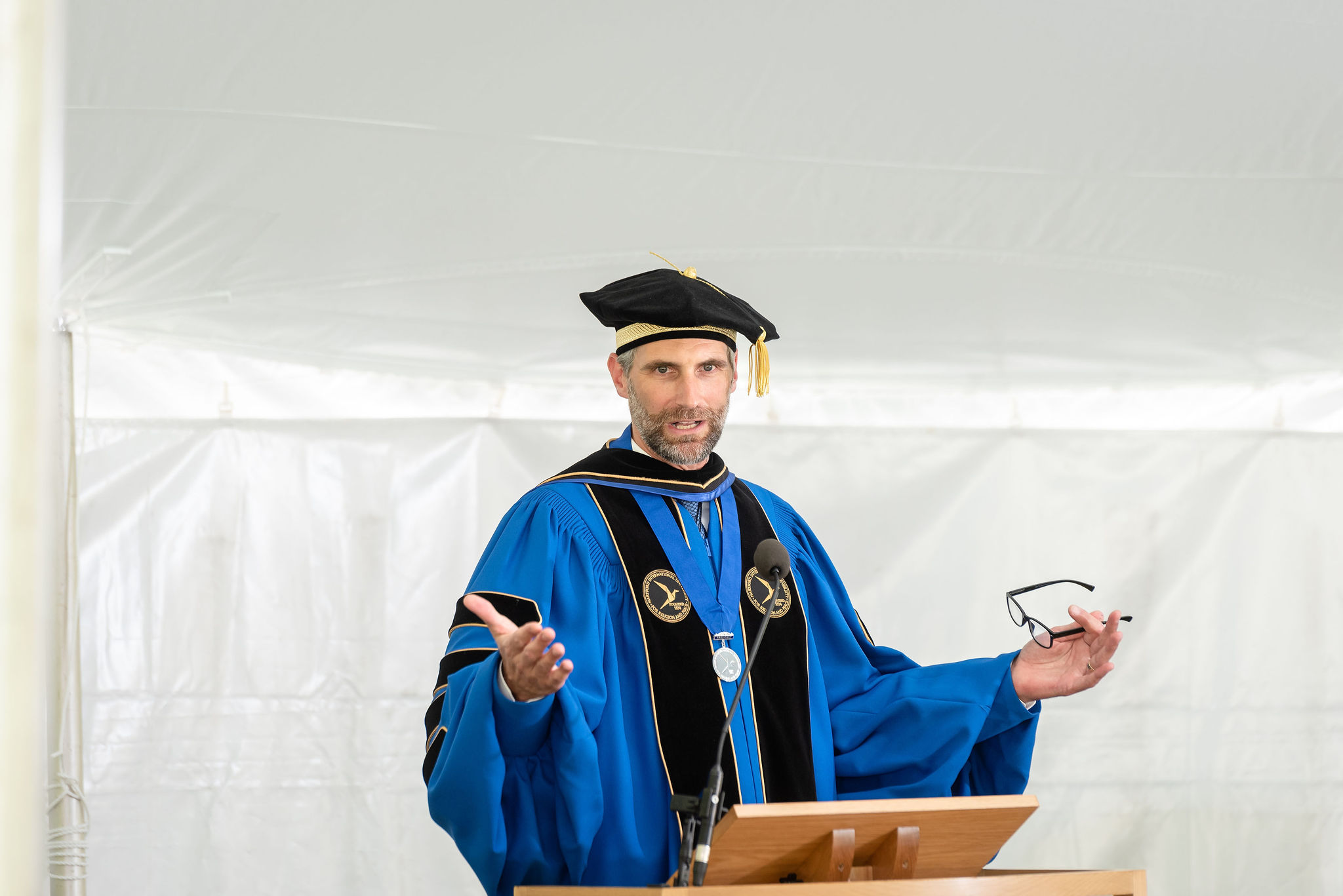 A tall man speaking behind a podium