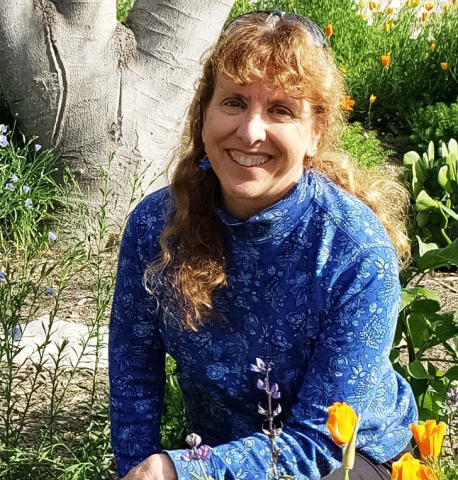 Dr. Lisa Dahill out doors with trees and flowers