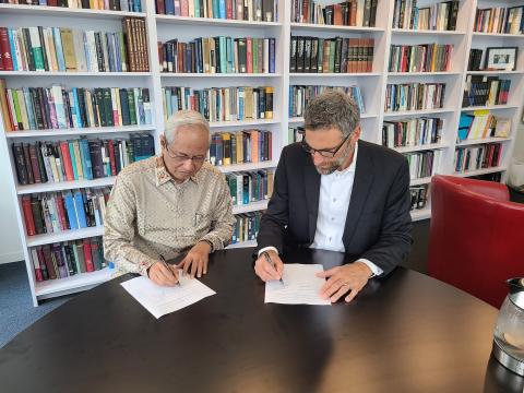 Two men signing papers at a table